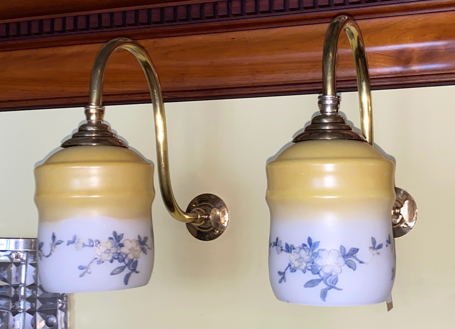 A pair of English brass gasolier wall lights with floral painted opaque wall glass shades, height 26cm